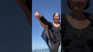 Granny in her 70s balancing on one leg on the beach