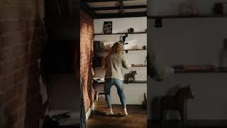 A woman cleaning the shelves and its contest while dancing