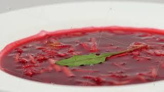 Red Borsch with meat in plate. A delicious red borscht with sour cream and herbs on a white plate