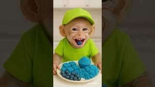 cute baby monkey eating blue food 